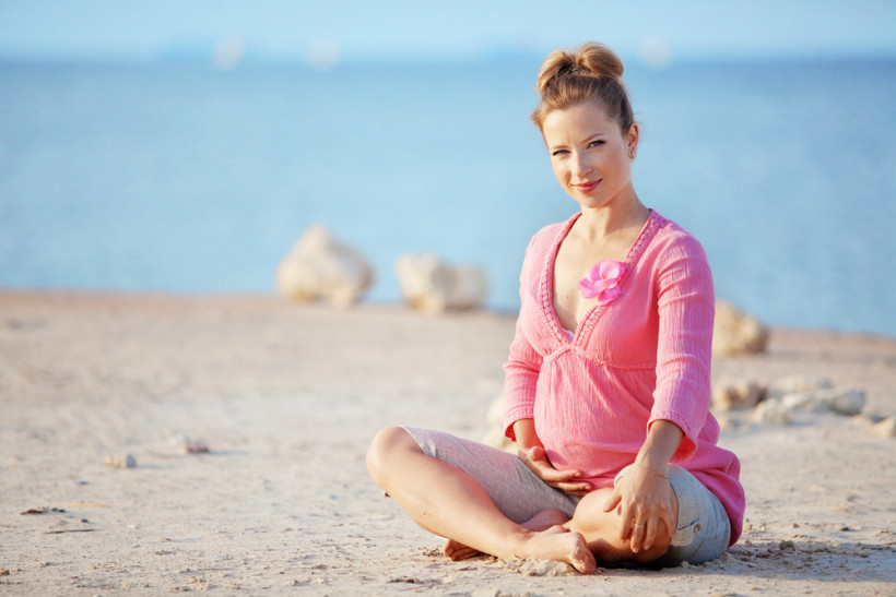 Беременная сидит на пляже