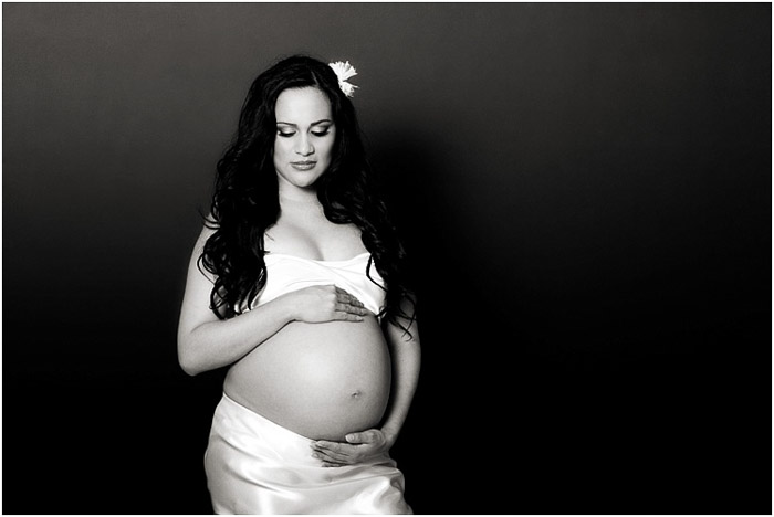 Black and white portrait of a pregnant woman holding her stomach 