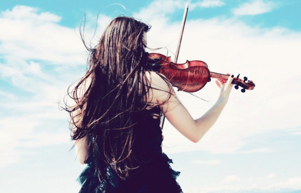Девушка играет на скрипке у моря