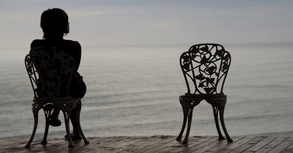 Женщина сидит одна у моря.