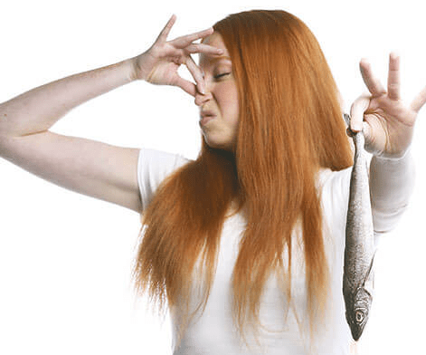 Девушка закрыла нос от запаха рыбы
