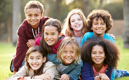 Group Of Children Lying On Grass In Park.