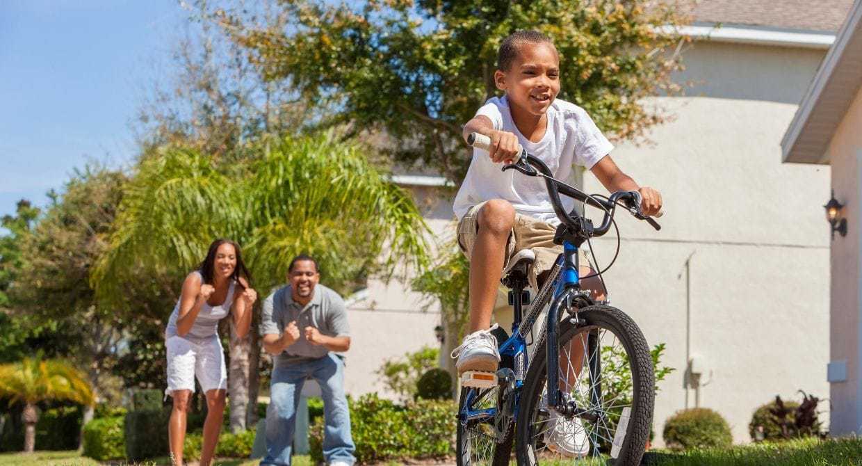 boy riding his bike with parents cheering